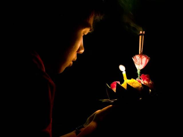 A man prepares to release a krathong into the river
